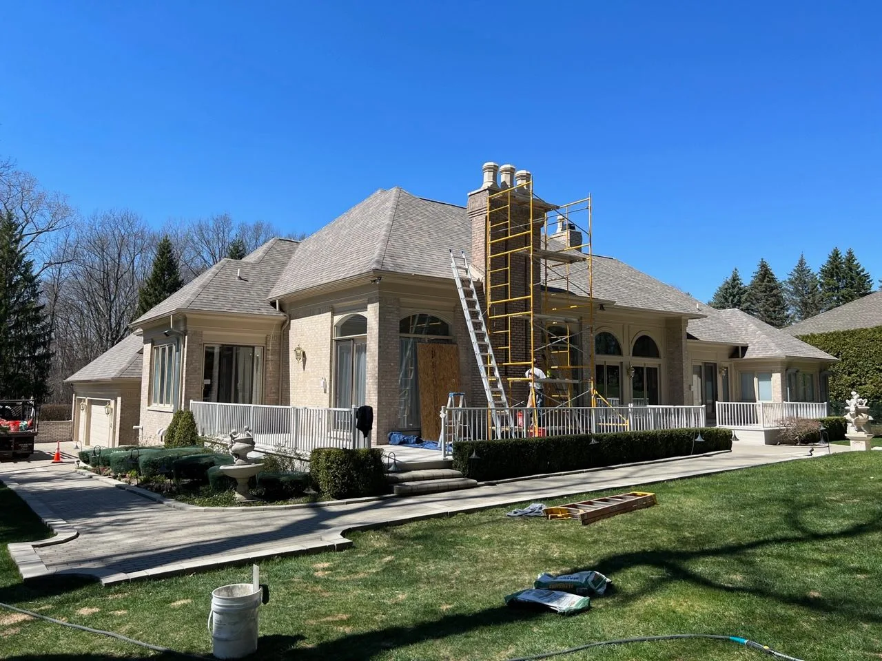 Crown Contracting crew working on a chimney with scaffolding at a brick home