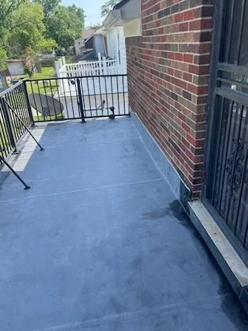 Finished flat roof deck with new membrane next to a brick wall