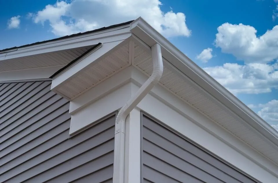 New white seamless gutter and downspout on a gray sided house