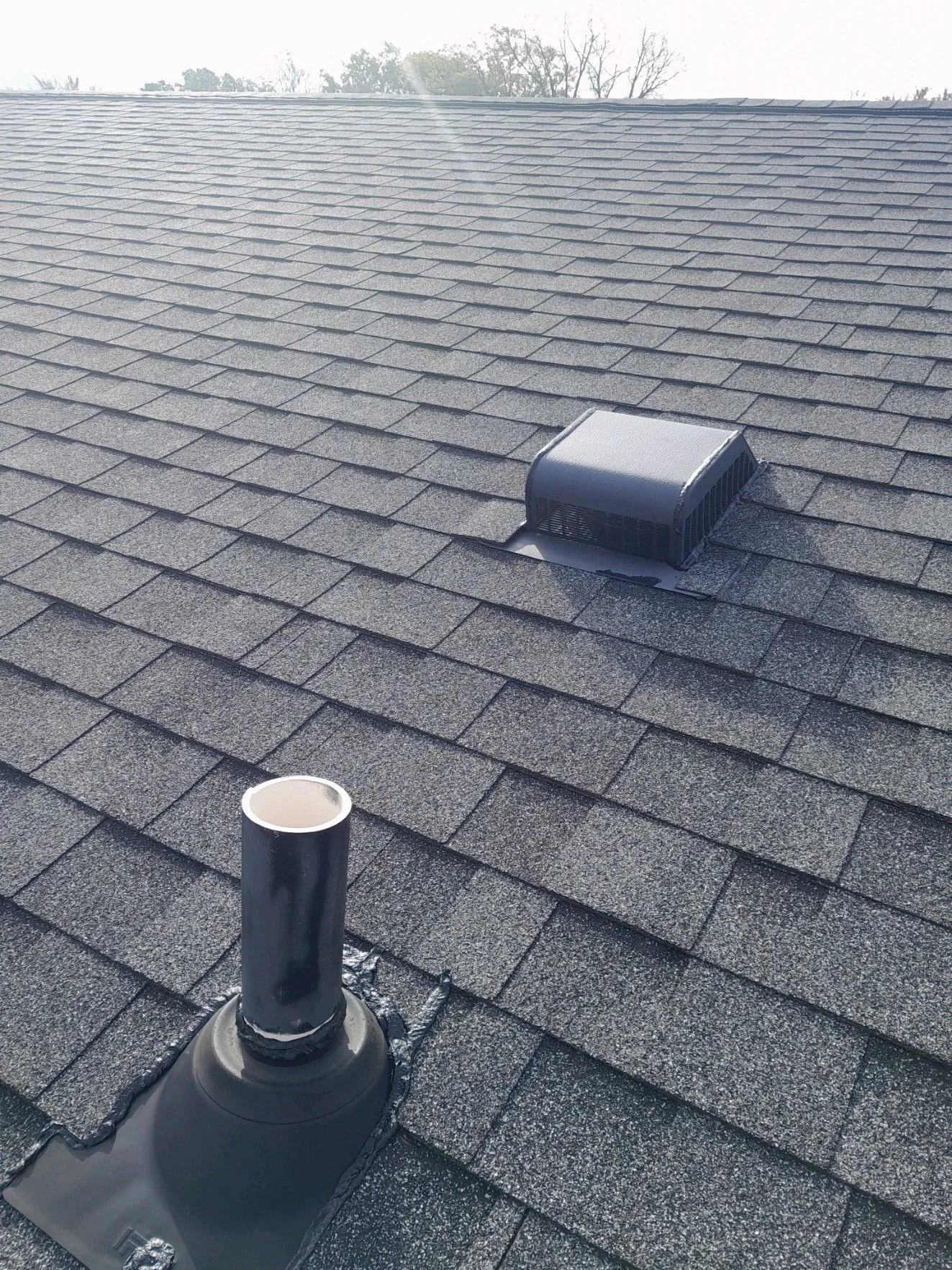 Roof vents and pipe boots on a shingle roof after repair