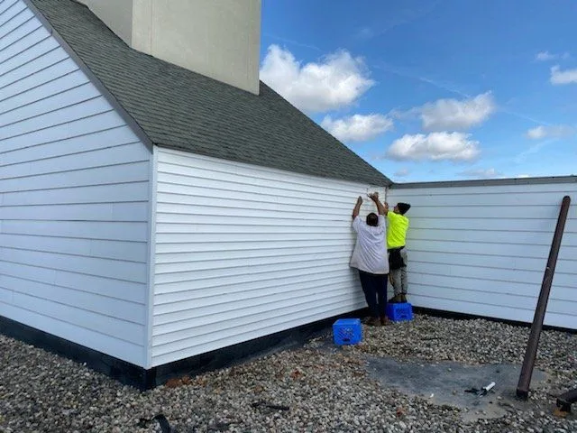 Crown Contracting crew installing white vinyl siding on a building